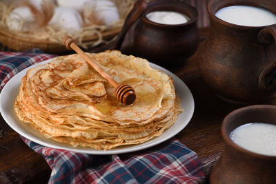 Homemade thin pancakes with honey stacked in a stack, on a wooden table 