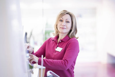 Smiling pharmacist arranging products at pharmacy store