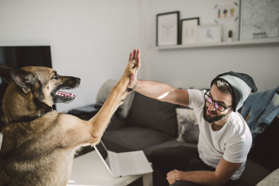 Young man at home giving high five with his dog