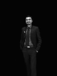 Portrait of young man standing against black background