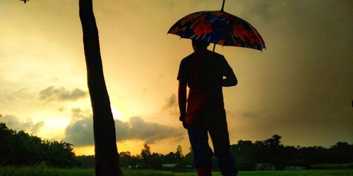 Silhouette man standing by tree during sunset