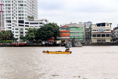 People on boat in city against sky