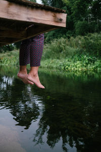 Low section of woman standing by lake