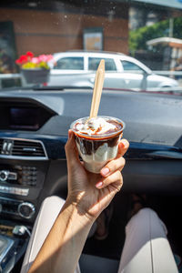 Midsection of person holding ice cream in car