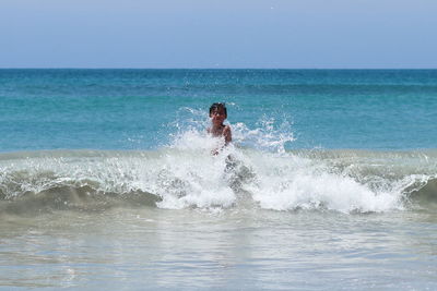 Man splashing water in sea against sky