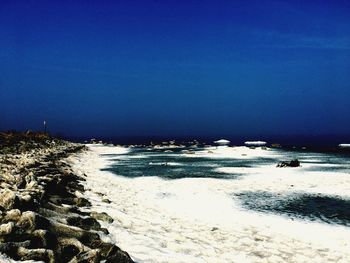 Scenic view of beach against clear blue sky