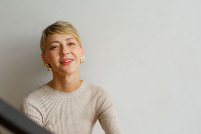 Portrait of young woman standing against wall