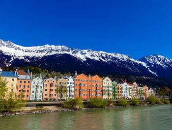 Buildings by mountains against clear blue sky