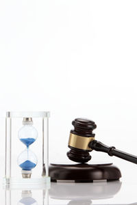 Close-up of gavel with hourglass against white background