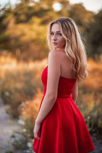 Portrait of beautiful young woman while standing against plants