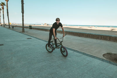 Man riding bicycle on sea against clear sky