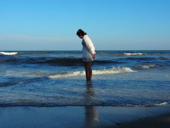 Full length of man standing on beach against clear sky