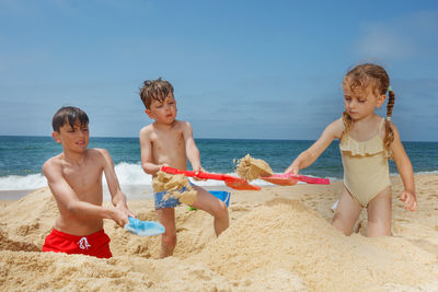 Rear view of boy playing with sand at beach