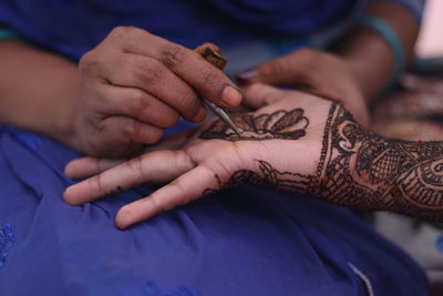 Close-up of woman applying henna tattoo on hand