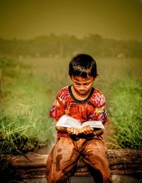 Full length of boy sitting on field