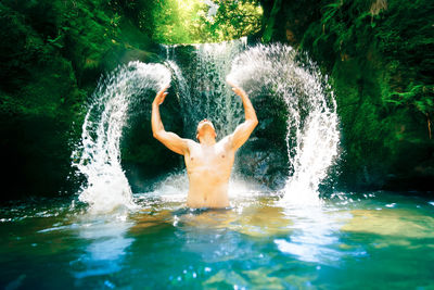 Full length of shirtless man splashing water