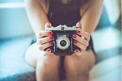 Midsection of woman holding camera