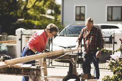 Senior couple measuring wooden plank at yard