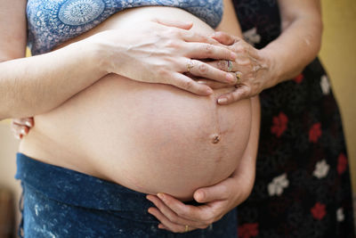 Midsection of pregnant women touching abdomen