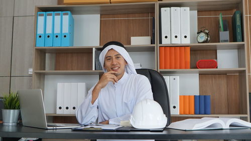 Portrait of smiling young woman working at desk in office