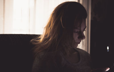 Woman using mobile phone while sitting at home