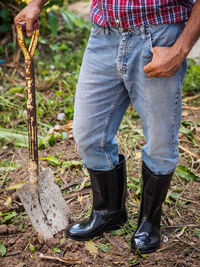 Low section of man holding spade while standing on land