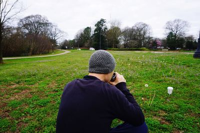 Man photographing on field against sky