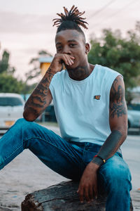 Portrait of young man looking away while sitting outdoors