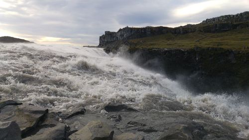 Scenic view of waterfall against sky