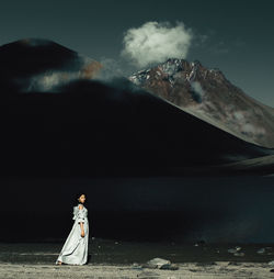 Portrait of woman walking by lake against mountains and sky