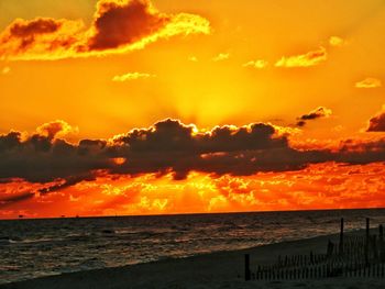 Scenic view of sea against dramatic sky during sunset