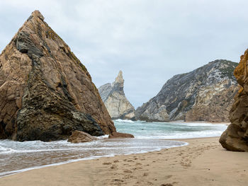 Rock formations on beach against sky