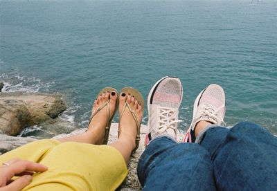 Low section of women relaxing on sea shore