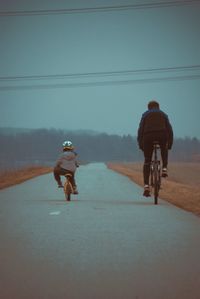 Rear view of man and child riding bikes