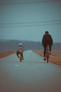 Rear view of woman riding bicycle on road