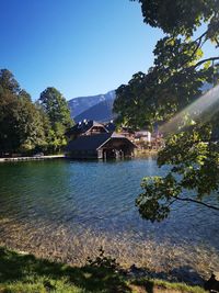 Scenic view of lake by trees and mountains against clear sky