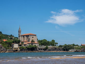 Building by sea against blue sky