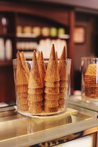 Close-up of ice cream cones in glass container at parlor