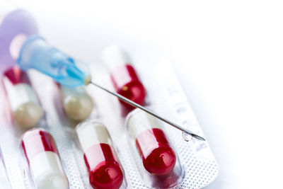 Close-up of capsules with syringe on white backgrounds