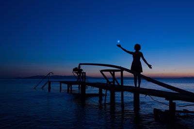 Silhouette fishing net at sea against clear blue sky