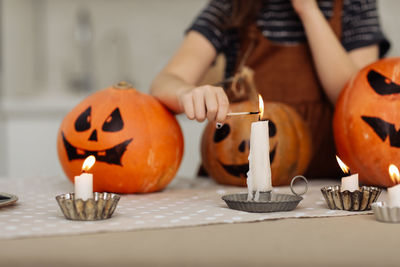 Midsection of woman holding jack o lantern on table