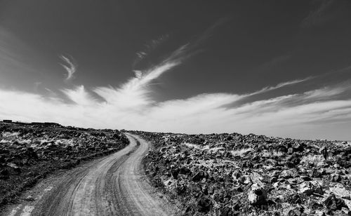 Road amidst field against sky