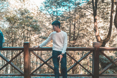 Man standing by railing in forest