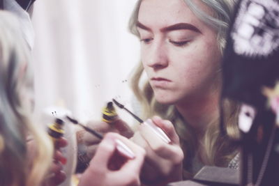 Close-up of young woman applying mascara while reflecting on mirror