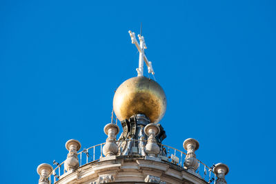 Low angle view of statue against building against clear blue sky