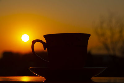 Close-up of coffee cup against orange sky