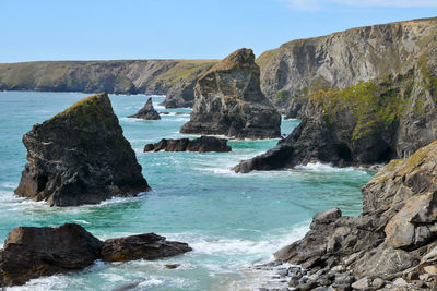 Rock formations by sea against clear sky