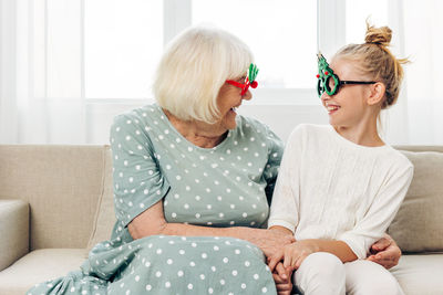 Mother and daughter sitting on sofa at home