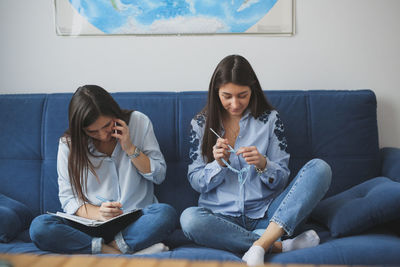 Two women with long hair sew in a bright real room, close-up. concept handwork and small business,