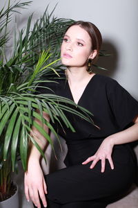 Portrait of young woman standing against plants